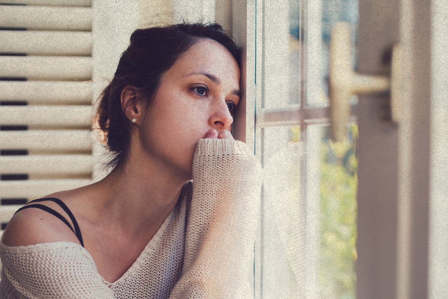 Mujer junto a una ventana en actitud reflexiva